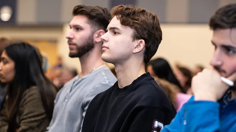 A group of students pay attention from the crowd during a President's Forum event