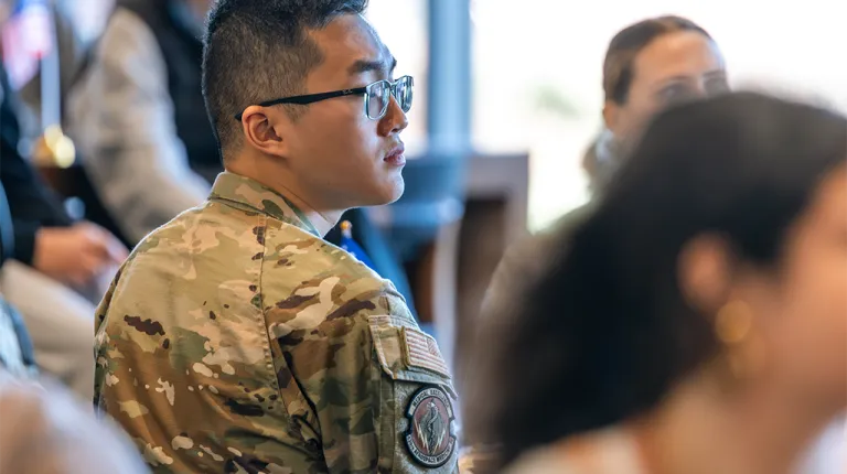 A student wearing an army uniform sits in an audience