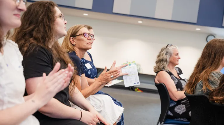 Audience members clap for a presentation