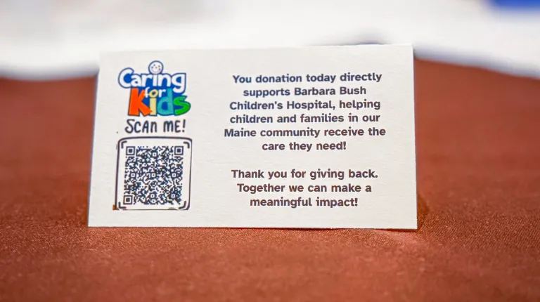 A notecard with a donation QR code link to the Caring for Kids fundraiser