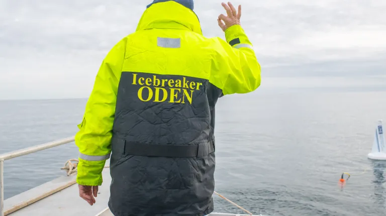 UNE boat pilot Tim Arienti gives an "OK" sign with his hands to signal the buoy is deployed successfully