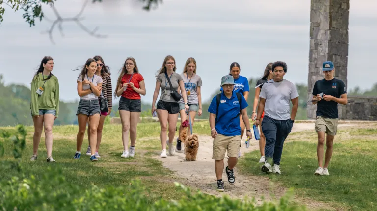 Campus tour guide gestures toward Jack S. Ketchum Library while speaking to prospective students.