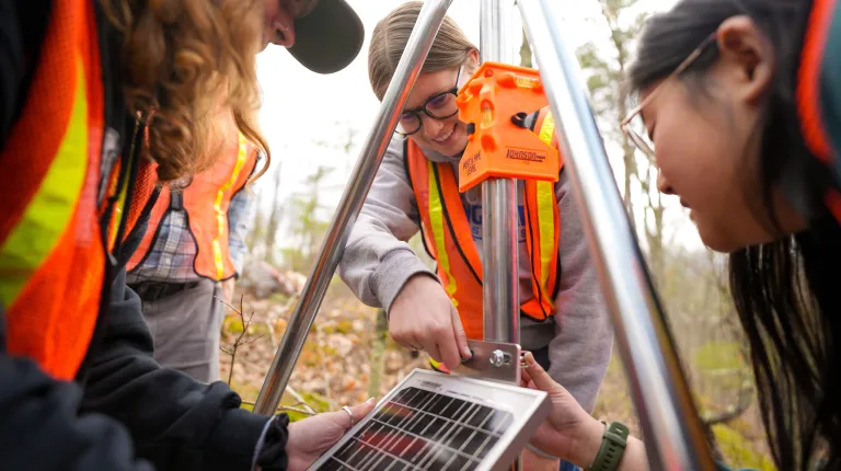 UNE students assemble components of a weather station in UNE's research forest