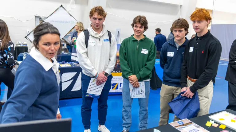 A group of male students speaks with a job recruiter