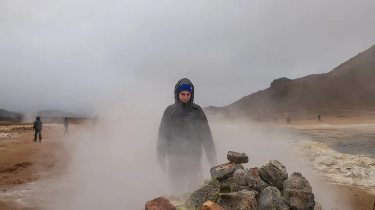 A student walks through dense fog on a rocky landscape