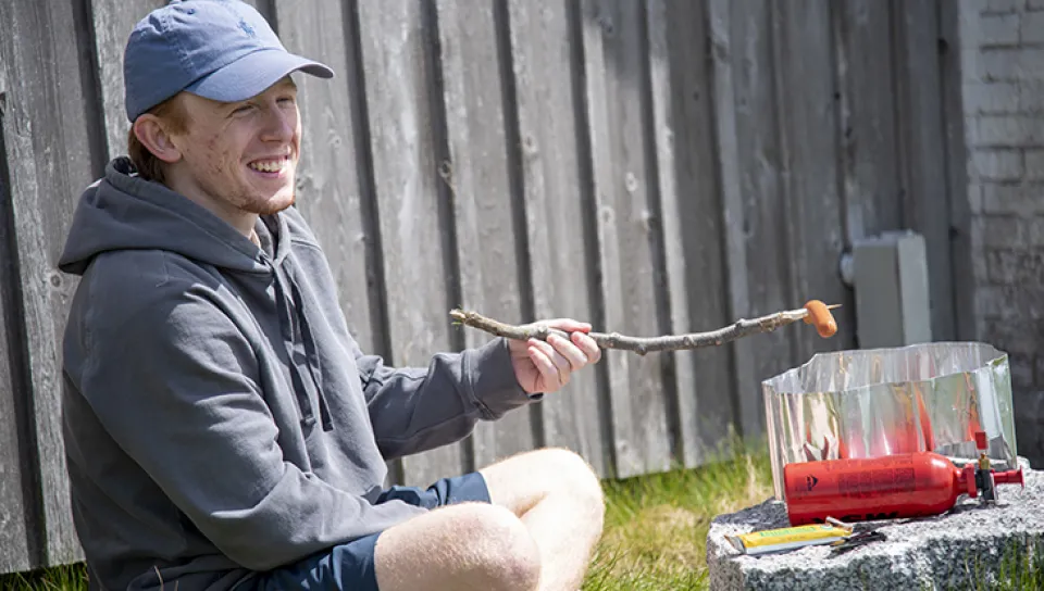 Cullen Hunt roasts a hot dog over a fire he built using a WhisperLite grill