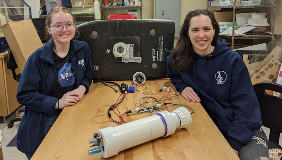 Two U N E students pose with their project in the Makerspace
