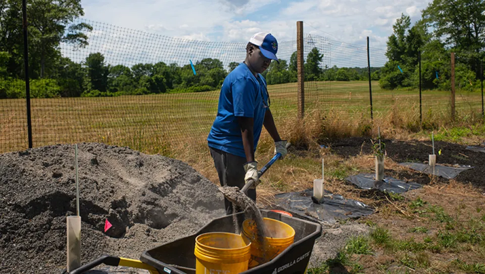 A boy shovels soil into buckets