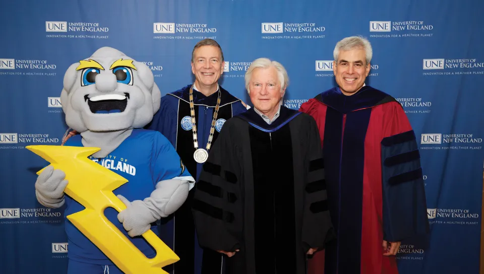 President Herbert and two U N E faculty members pose with U N E mascot Stormin' Norman