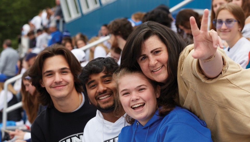 A group of students and a parent having a good time at a U N E football game