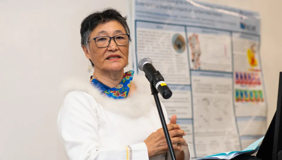A woman speaks in front of a research poster