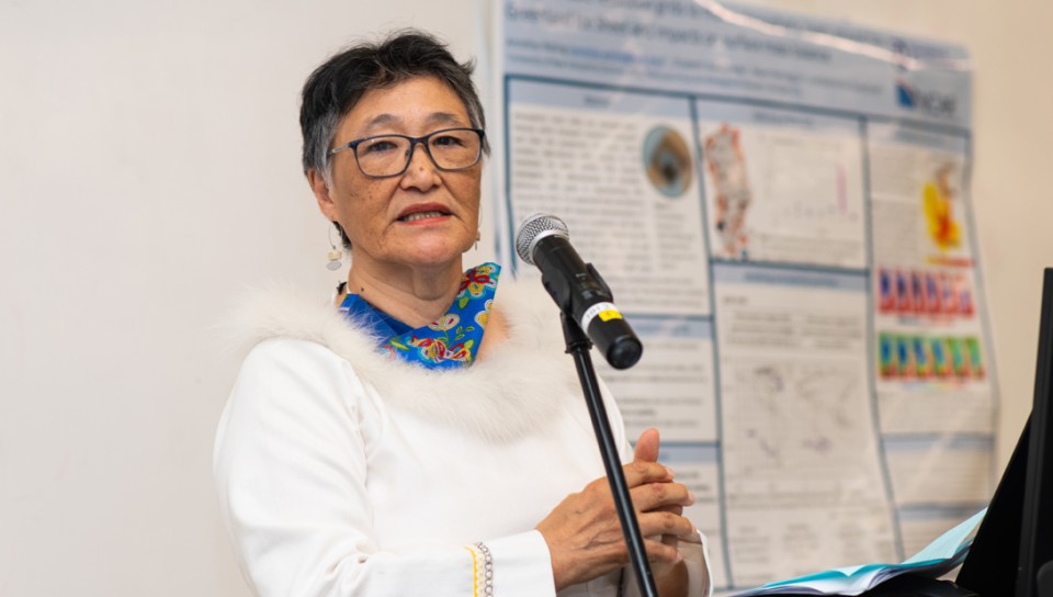 A woman speaks in front of a research poster
