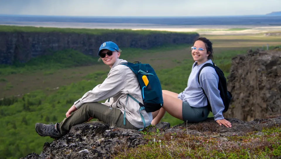 Students sit on a ledge while hiking on a travel trip to Iceland