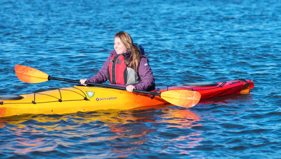A student kayaks in a river