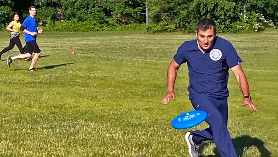 A graduate student chases a frisbee during a game