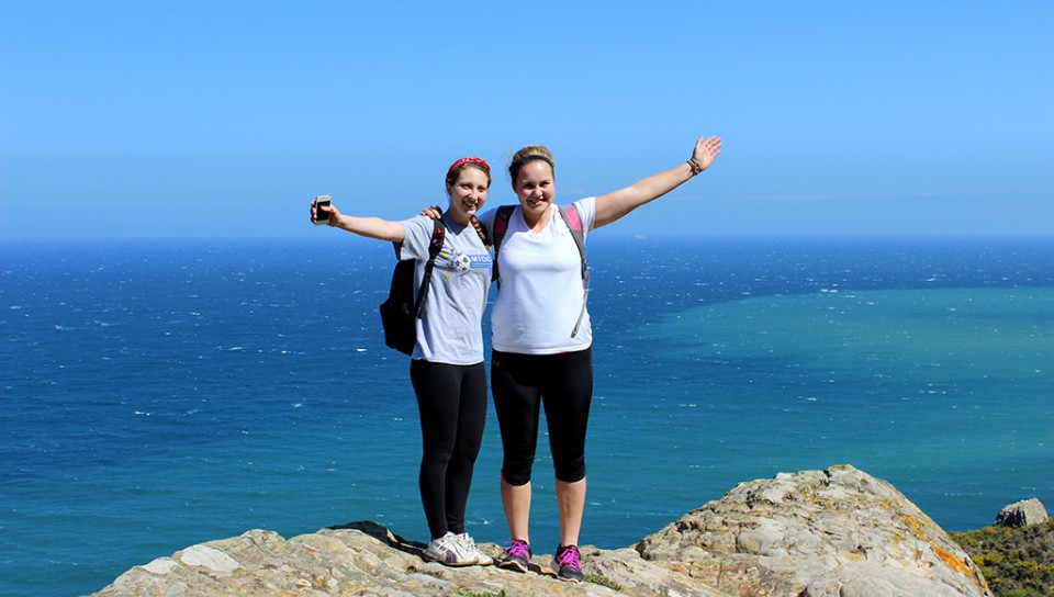 Two students on top of a mountain overlooking the ocean