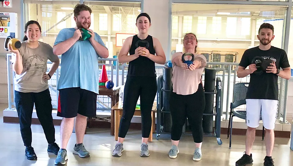 Five students each holding a type of weight available in the Finley Recreation Center
