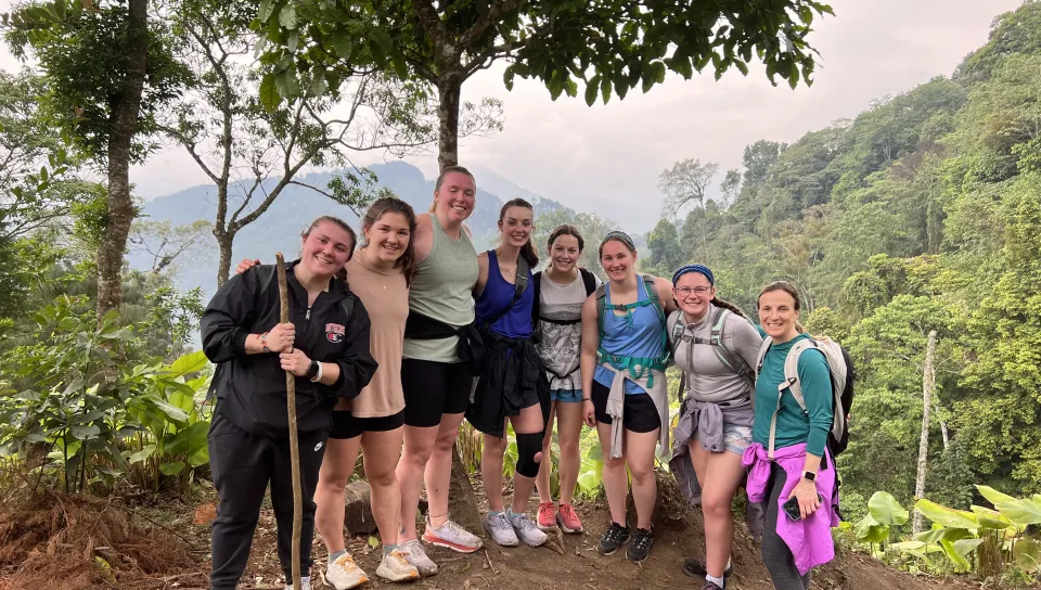 A group of students pose at the top of a mountain following a hike