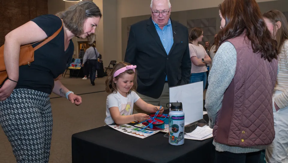 A child plays with an adaptive toy at a display table