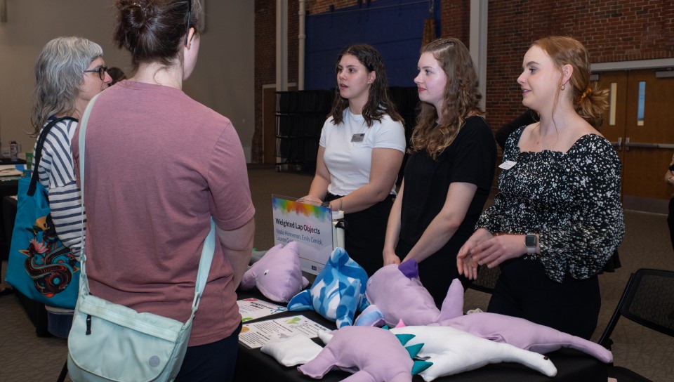 Three students showcase their weighted animal plushes, designed to help with anxiety