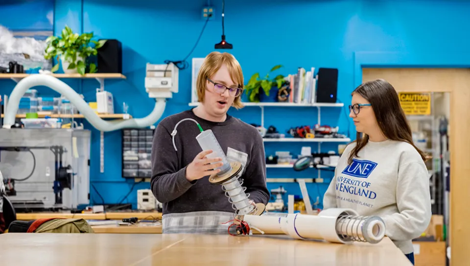 Two U N E students show their technology projects to one another in the Makerspace