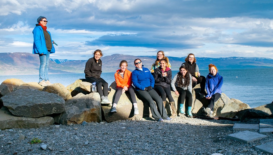 A group of students sit near the ocean in Iceland