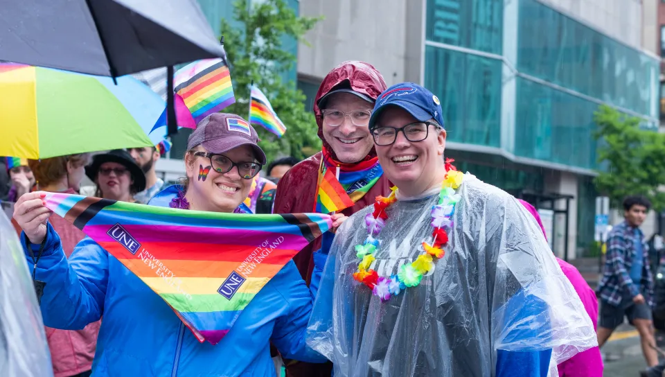 Assistant Provost for Diversity, Equity, and Inclusion Shannon Zlotkowski and company display UNE-branded pride merch, including a bandana