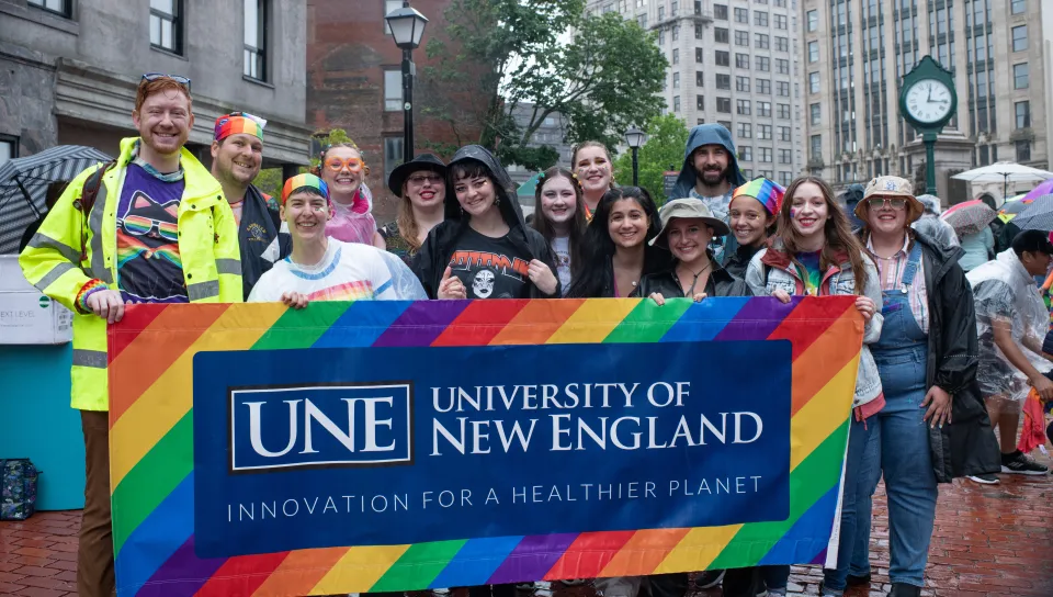 UNE community members gather with a UNE Pride banner in Monument Square in Portland