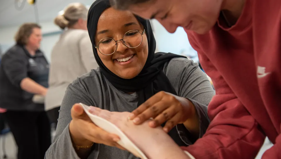 An Occupational Therapy student practices applying a wrist brace to another student