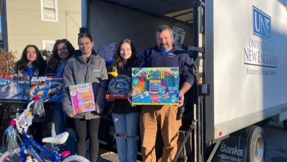 Students and volunteers pose in front of a box truck holding toys and gifts for Seeds of Hope