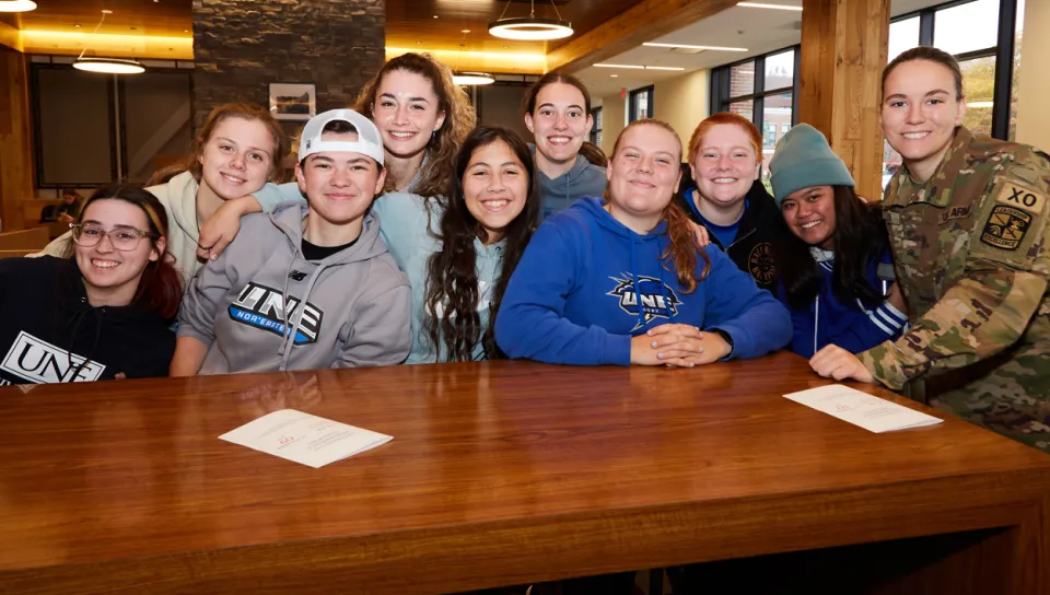 A group of U N E students smile with a veteran