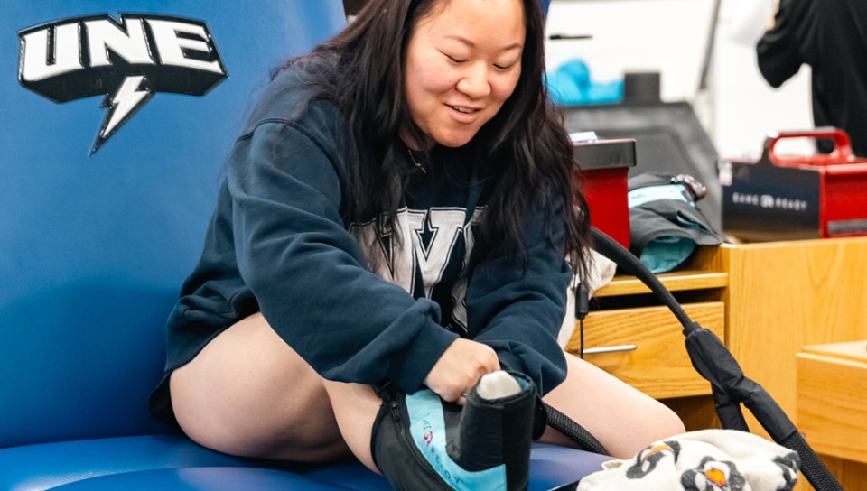 An athletic training student practices icing a foot injury on themself during class
