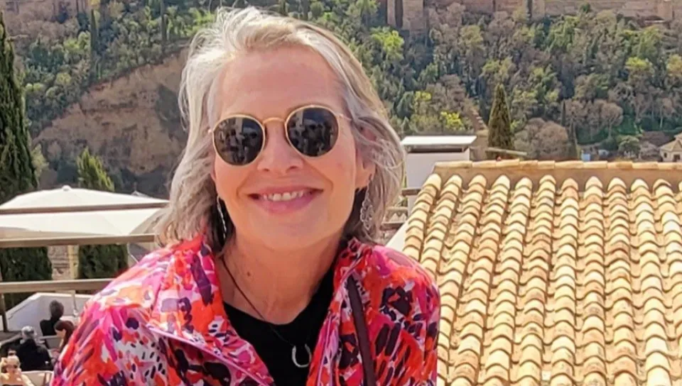 A woman smles for a photo in front of a countryside Spanish city 