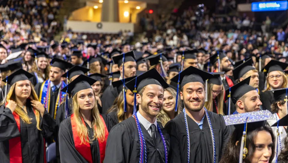 A crowd of UNE graduates smiles for a photo