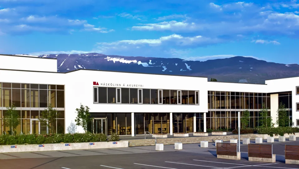 A white building with a lot of windows in front of a mountainscape and blue skies