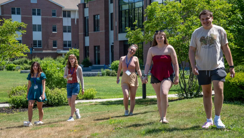 Several students walk on the UNE lawn