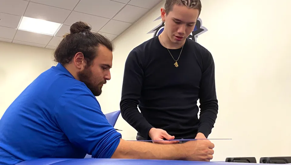 An athletic training student measures the length of another student's arm