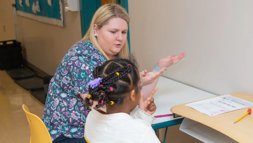 An education student helps an elementary school student count with their hands