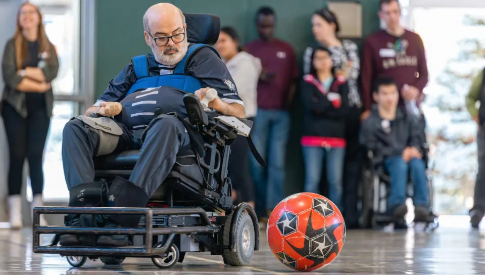 A man in a wheelchair plays power soccer