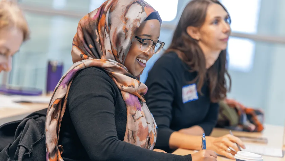 Two female students take notes at a desk