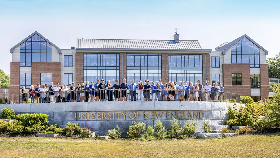 College of Business students and faculty stand in front of the UNE Commons on the Biddeford Campus