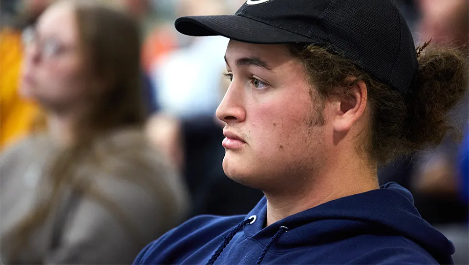 A UNE student in a ballcap listening to the guest speakers