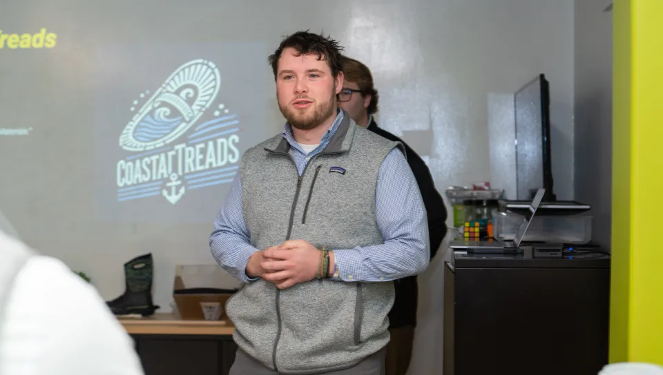 A student presents a slideshow to a room of people