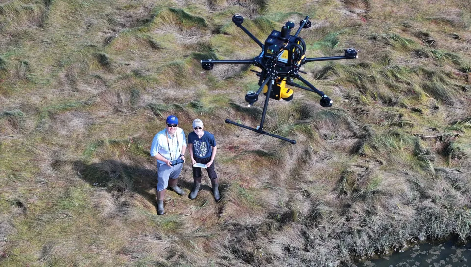 Johanna Birchem with Will Kotchtitzky flying a drone on the marsh.