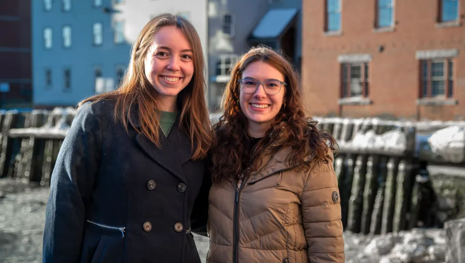 Two women pose in front of the Portland waterfront
