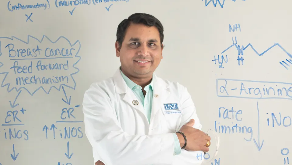 Portrait of Sri Mohan against a whiteboard with chemical formulas
