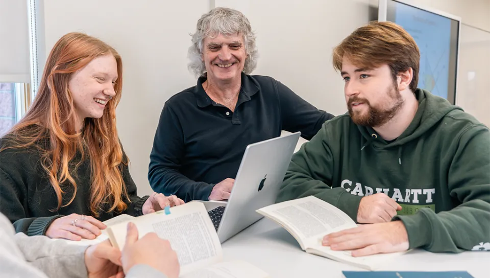 A professor talks to two students in an economics class
