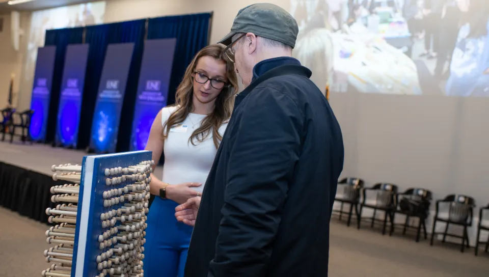 A student showcases a pin art project  