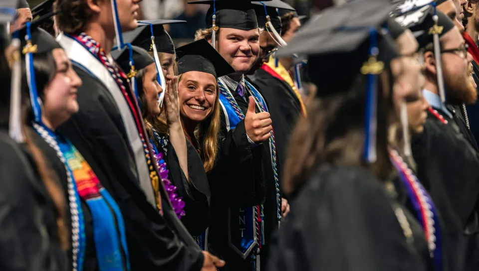 A graduating student smiles through a crowd of her peers