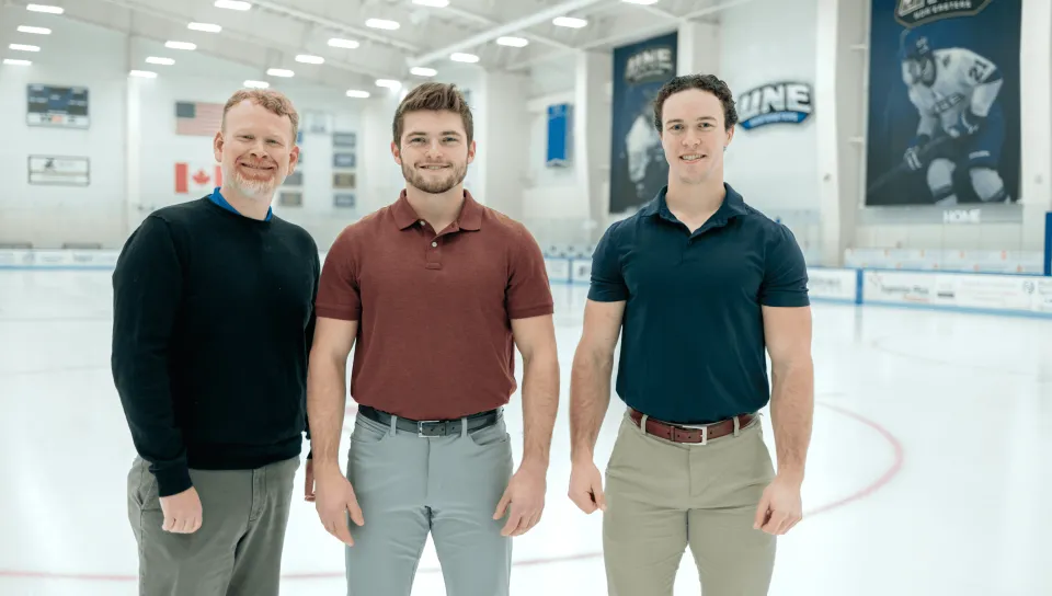 UNE professor Jeremy Pare and students Joey Stanizzi and Dylan Schuett pose in the UNE ice rink